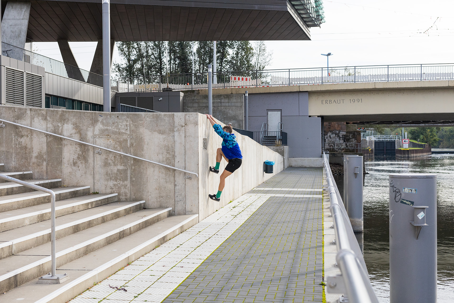 Eine Person trainiert Parkour und klettert im Outdoor-Bereich auf eine Mauer.